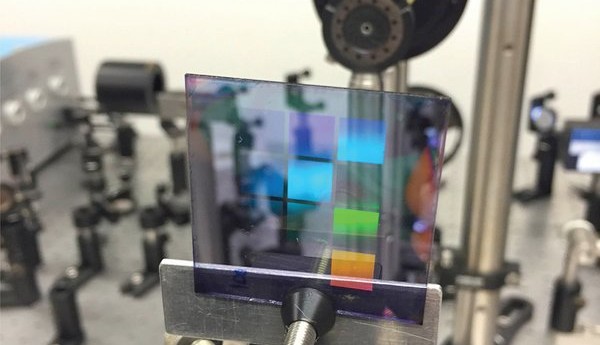 Een proefstuk van het nieuwe lasermateriaal. Het bevat tien vierkantjes met daarin telkens een ander patroon van zilverstippen. De zichtbare kleuren op het proefstuk zijn niet het laserlicht (de laser is niet aan op deze foto), maar zijn reflecties net als bij een CD (foto: Alexei Halpin, TU Eindhoven).